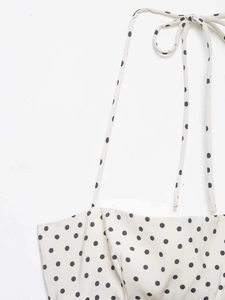 Détail de l'encolure licou et du nœud papillon sur la robe mi-longue à pois noirs