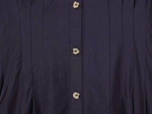 Détail de robe plissée violette avec boutons en écaille de tortue et texture en coton