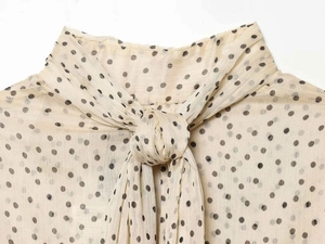 Detailed view of polka dot chiffon fabric with tie-neck bow and ruffled collar detail