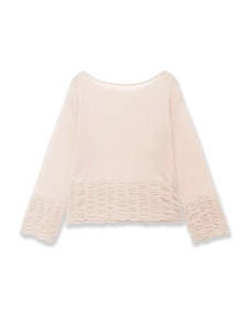 Detailed view of apricot knitted top featuring ruffled hem and ribbed sleeve cuffs