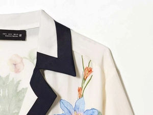 Detail of white floral shirt collar with black scalloped trim and brand size label