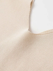 Detailed macro view of beige ribbed knit sweater showing premium texture and neat stitching