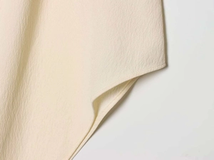 Vista macro dettagliata della trama del tessuto plissettato beige con cucitura singola