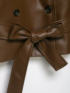 Detail of dark brown faux leather jacket with textured grain, double buttons and belted waist