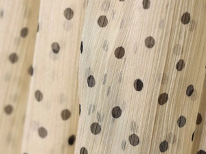Macro detail of beige polka dot chiffon fabric with elegant vertical pleated texture