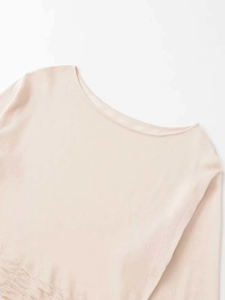 Close-up detail of the elegant boat neck design and fine knitting texture on apricot sweater