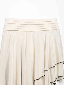 Détail de jupe en satin crème avec taille plissée et bordures noires contrastées