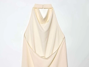 Dettaglio del top a collo alto color crema con texture increspata e design a schiena nuda