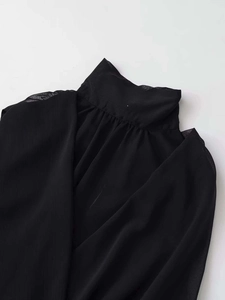 Close-up of pleated stand collar on a black sleeveless chiffon blouse for women
