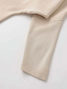 Close-up of beige V-neck sweater showing fine knit texture and ribbed cuff detail