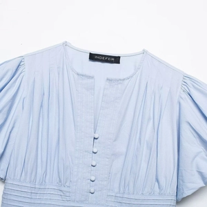 Light blue V-neck blouse with puffed sleeves, ruffled details, and matching front buttons