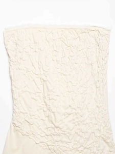 Detail of cream off-the-shoulder top featuring pleated texture and fine lace trim