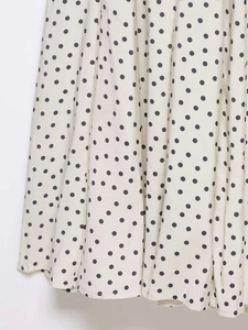 Détail du tissu léger de robe midi blanc cassé avec un motif classique à pois noirs