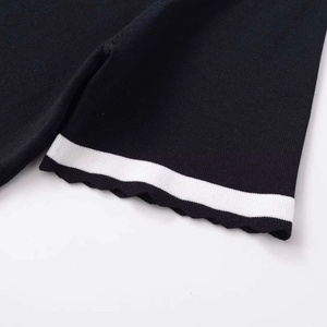 Women's black knit sweater with white contrast stripe and wavy ruffled edge detail
