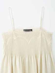 Detail of pleated beige camisole featuring delicate eyelash lace trim and thin straps