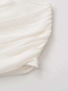Detail shot of textured white knit fabric featuring elegant ruched sun pleats design