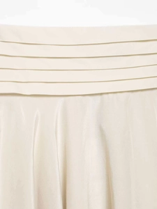Détail d'une jupe en satin avec des plis horizontaux superposés et un éclat champagne doux