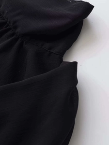 Close-up of black sleeveless chiffon top showing fine fabric texture and neat stitching