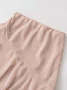 Détail de la taille haute et du tissu en mousseline lisse de la jupe rose clair