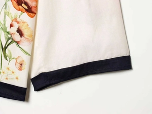 Detailed close-up of floral twill fabric and navy blue piped edge on long sleeve top