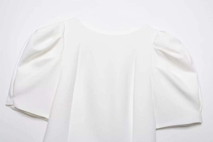 Détail des manches bouffantes blanches et de la texture mousseline sur un chemisier d'été