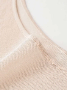 Close-up detail of fine apricot knit fabric showing high-quality stitching and texture