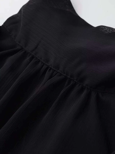 Detailed view of black chiffon sleeveless shirt featuring a pleated stand-up collar and seams