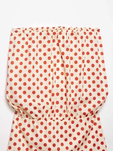 Dettaglio dell'abito a pois rossi con bordi elastici arricciati su tessuto di base beige