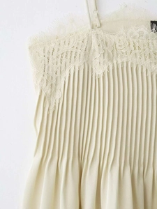 Detailed view of apricot camisole featuring pleated fabric and delicate eyelash lace trim