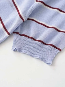 Close-up of ribbed cuffs on light blue knit sweater with white and red stripes