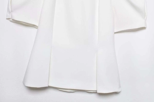 Détail de l'ourlet d'une chemise blanche avec plis centraux et texture de tissu premium