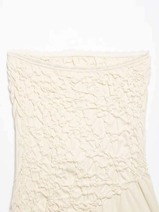 Detail of cream ruched tube top featuring delicate wavy lace trim and smocked fabric