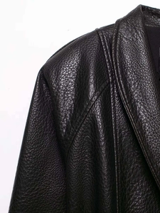Detailed macro view of black faux leather grain texture on shoulder and collar of jacket