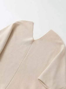 Detail view of the beige V-neck knitted sweater featuring fine texture and vertical seam detail