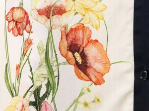 Detail of floral print on linen fabric with orange poppies and dark button placket