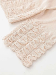Detailed close-up of apricot knitted fabric featuring elastic smocked hem and fine texture