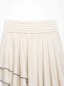 Détail d'une jupe beige clair à étages avec taille plissée et bordure noire fine