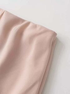 Vue détaillée du tissu en mousseline rose poudré avec plis souples et coutures fines