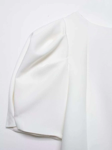 Détail de manches bouffantes courtes sur une chemise blanche avec plis et tissu tissé