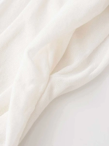 Close-up of white sun-pleated knit fabric texture with delicate woven details