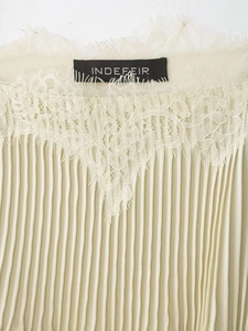 Detail of pleated beige fabric with delicate eyelash lace trim and V-shaped neckline