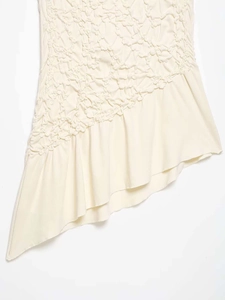 Detail of light beige strapless top with ruched fabric and asymmetric ruffle hemline