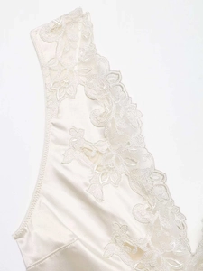 Close-up of the pearly white satin fabric and intricate floral lace on the bodysuit