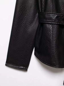 Macro shot of black faux leather jacket texture featuring lychee grain and stitching