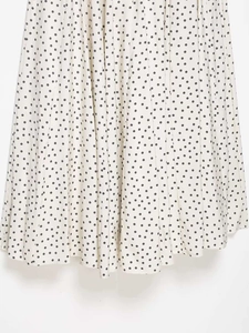 Détail du tissu d'une robe midi blanche à pois noirs avec une texture plissée et fluide