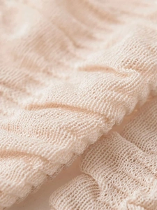 Macro detail of the beige knitted fabric with openwork pattern and ruffled hem texture