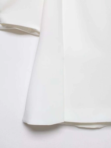 Détail de l'ourlet et de la texture sergée fine sur une chemise blanche à perles
