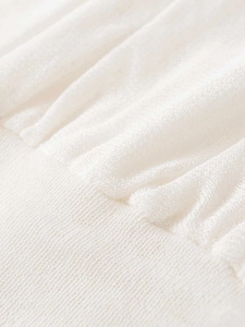 Macro detail of white pleated knit fabric showing fine texture and ruched design