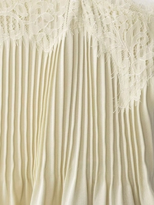 Detail of elegant beige lace trim and pleated fabric on a summer camisole top
