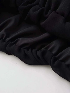 Macro shot of black chiffon fabric texture with delicate pleats and professional stitching